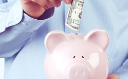 Male hand putting coin into a piggy bank